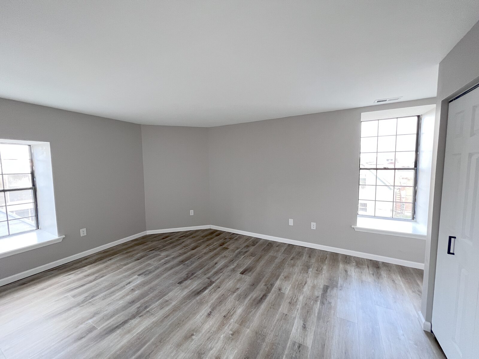 Bright corner bedroom with two windows and wide-plank flooring