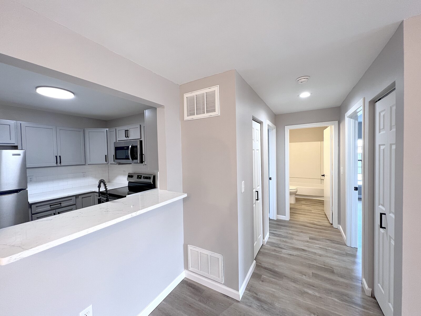Hallway with view into kitchen and bathroom beyond