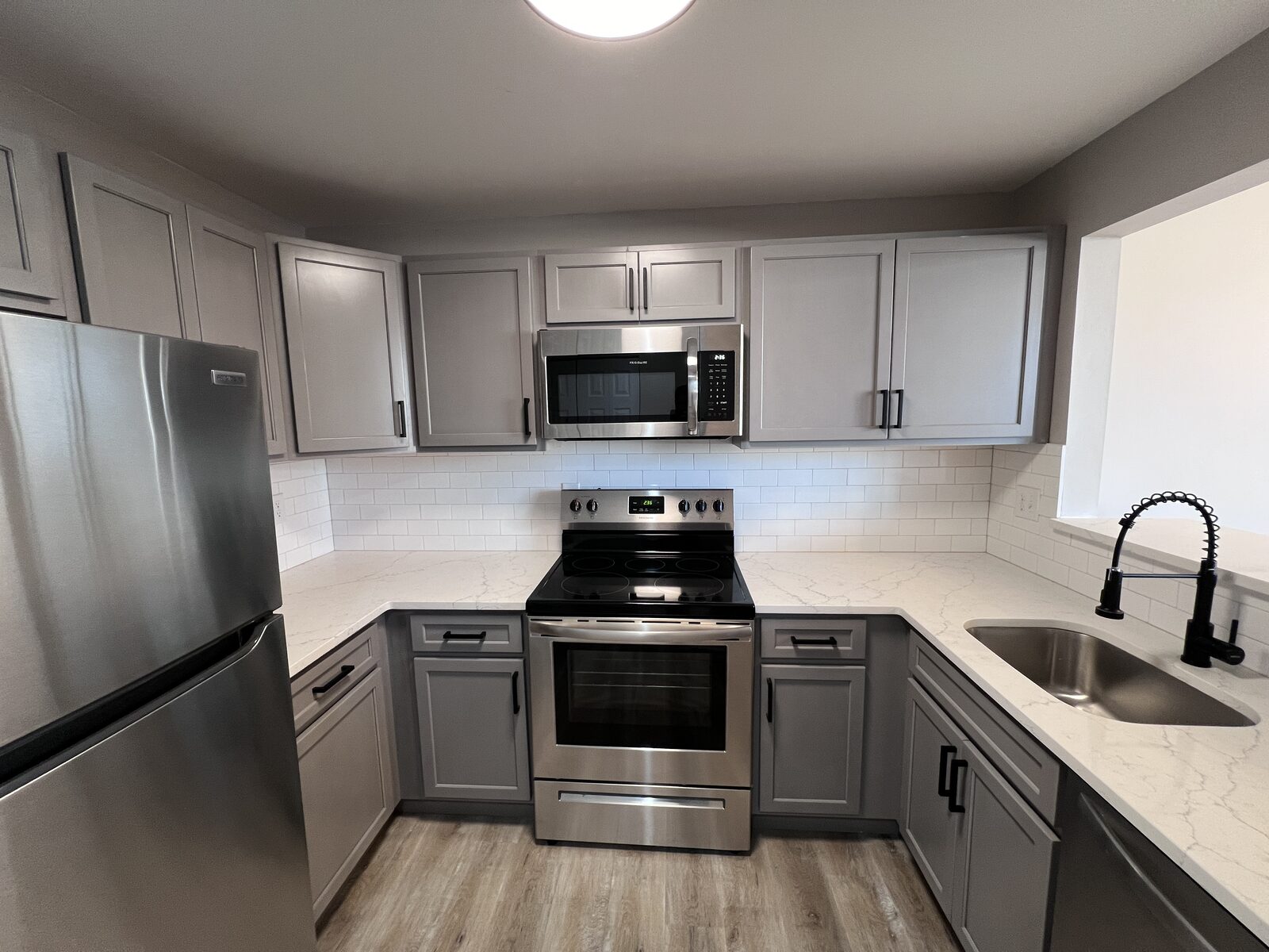 Renovated kitchen with quartz countertops, subway tile, and stainless appliances