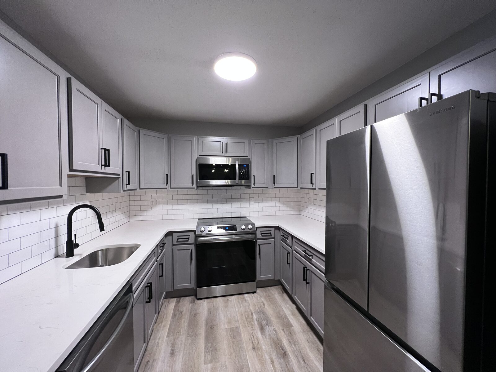 Wide view of renovated kitchen with gray cabinetry and subway tile